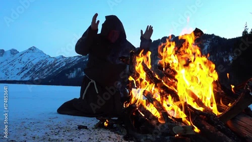 Monk franciscans are warming near fire in winter. Slowmotion 240FPS
 photo