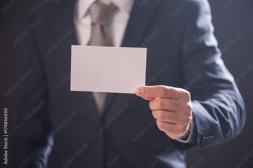 man's hand showing business card isolated on dark background man's hand showing business card isolated on dark background