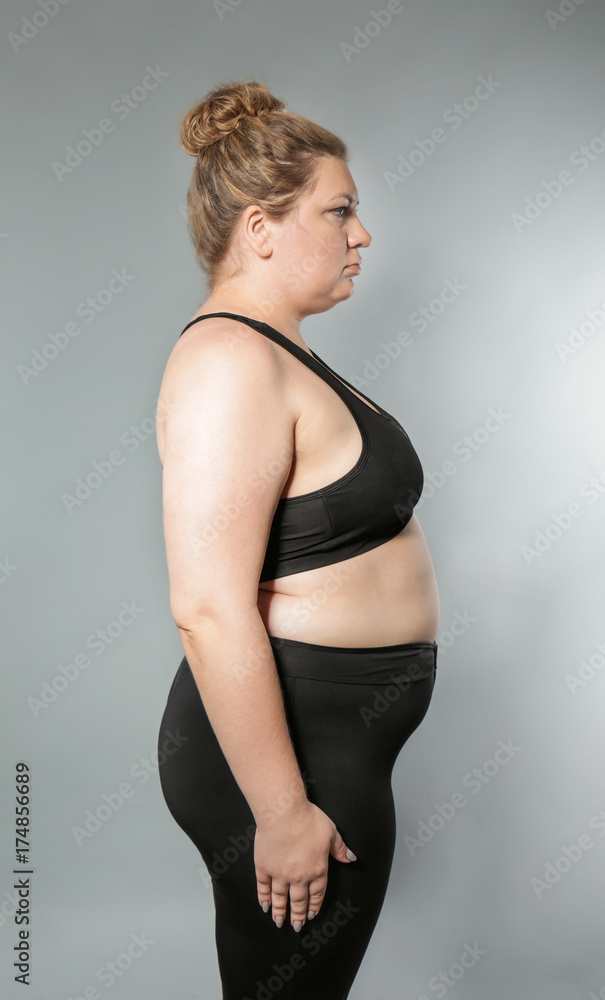 Overweight young woman on grey background. Weight loss concept Overweight young woman on grey background. Weight loss concept