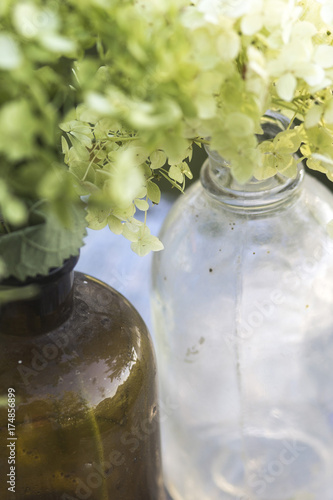 Brown and white glass bottles with hydrangeas in them