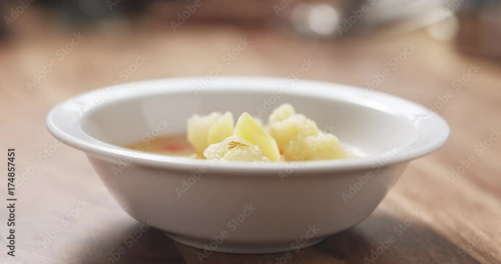 Closeup pouring cauliflower soup into bowl on wood table Closeup pouring cauliflower soup into bowl on wood table