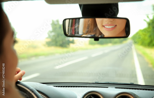 Woman looking in rear view ...