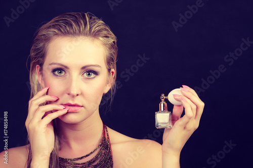 Beautiful woman with necklace holding perfume