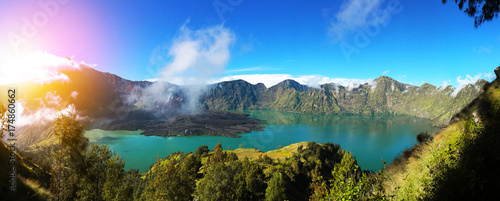Colorful panorama view of the crater in Rinjani mount in Lombok with sun light, Indonesia on a nice sunny day and blue sky
