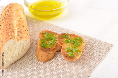 Fried bread with olive oil, garlic and herbs on a wooden table. Rustic style.