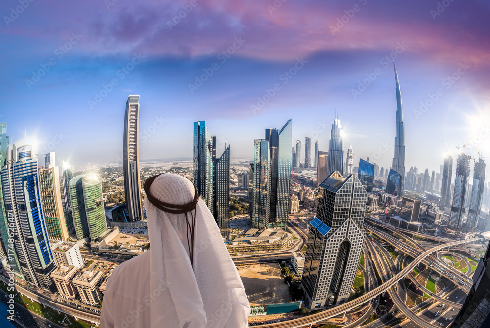 Obraz premium Arabian man watching cityscape of Dubai with modern futuristic architecture in United Arab Emirates.