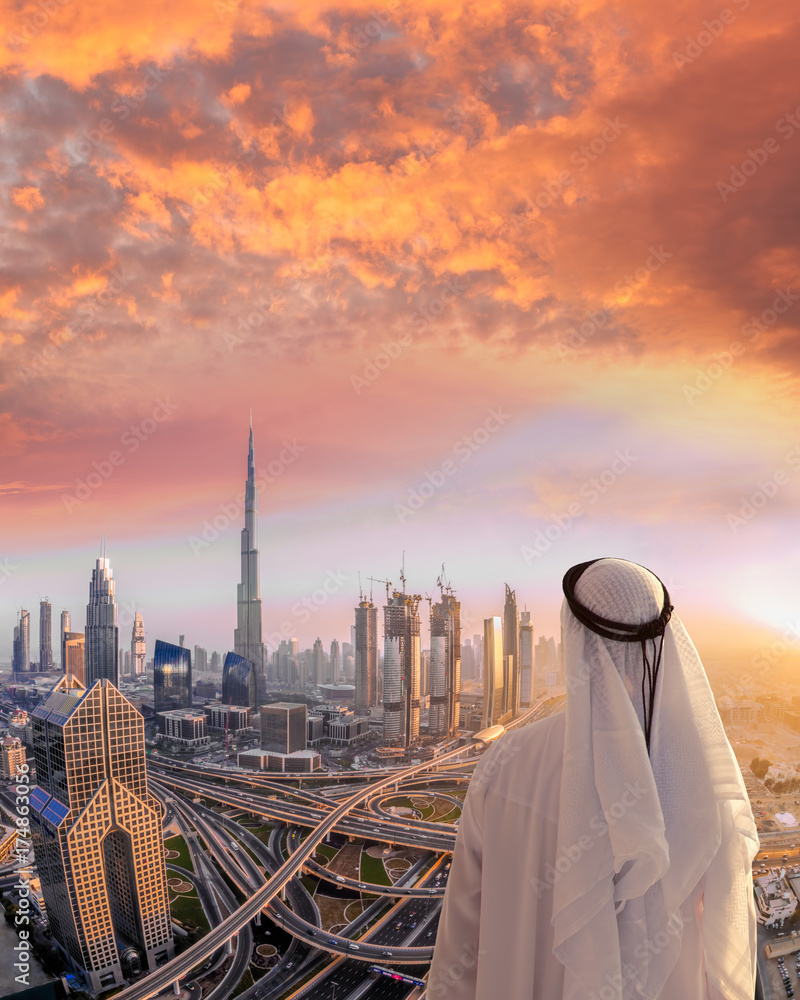 Naklejka premium Arabian man watching cityscape of Dubai with modern futuristic architecture in United Arab Emirates.