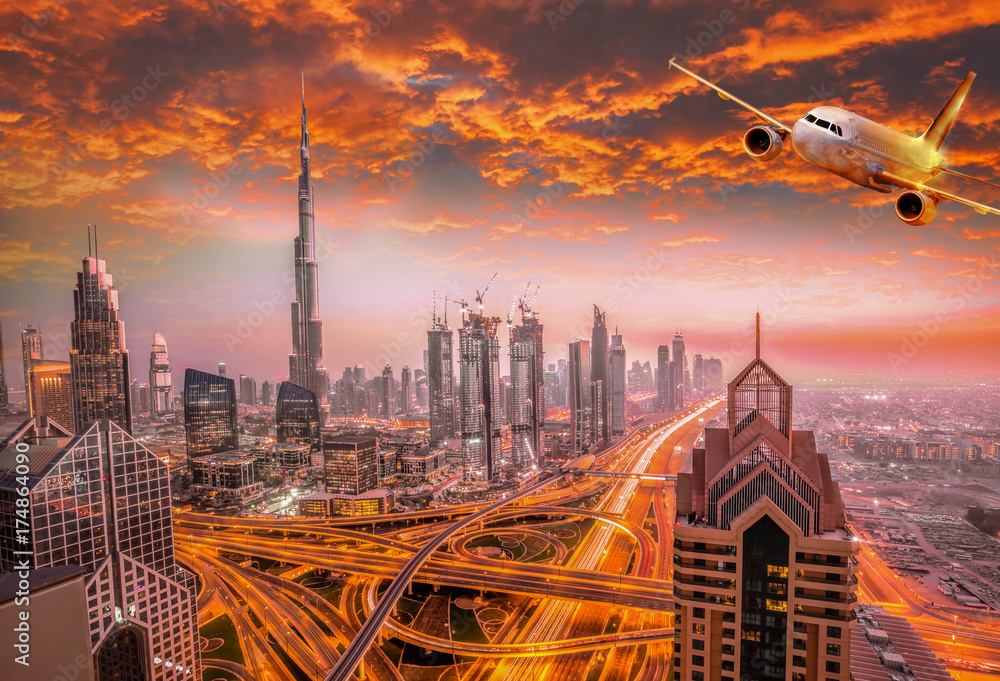 Fototapeta premium Airplane is flying over Dubai against colorful sunset in United Arab Emirates