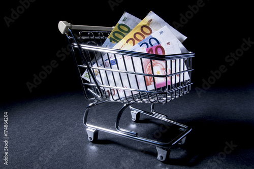 Supermarket shopping cart filled euro banknote. Isolated on black background. With copy space text. Studio Shot.
