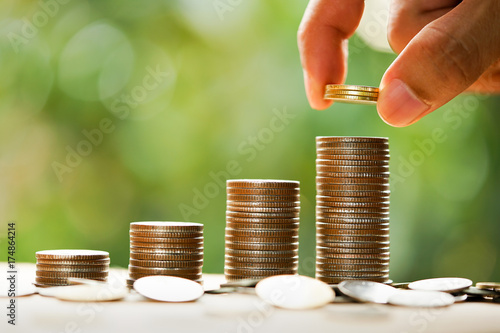 Man's hand put money coins to stack of coins. Money, Financial, Business Growth concept. photo