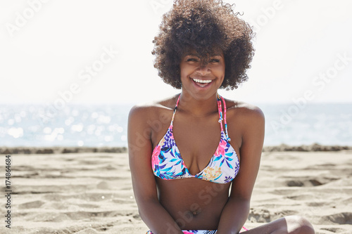 Young beautiful afro american woman on beach laughing