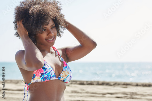 Afro american woman in colorful bikini holding hands on head