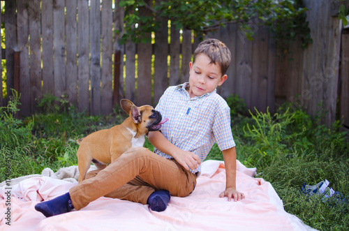 Happy laughing caucasian boy with french buldog puppies. Smiling ukrainian child playing with pets