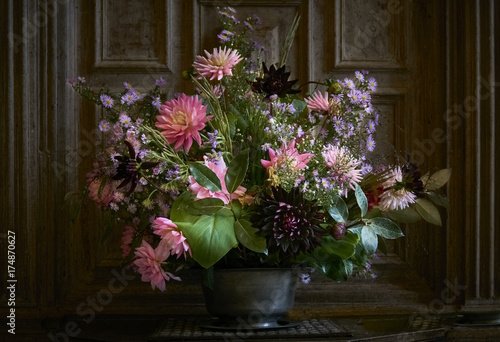 Fototapeta Autumn flower arrangement in a rustic pewter vase indoors in front of oak panell