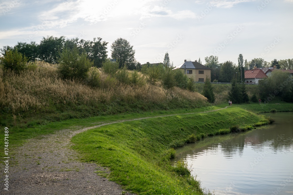 Chimneys of town and clouds with reflections in water reservoir on river Vah. Slovakia