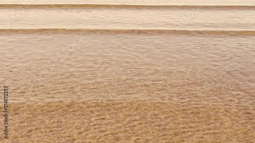 waves splash about the sandy beach. 