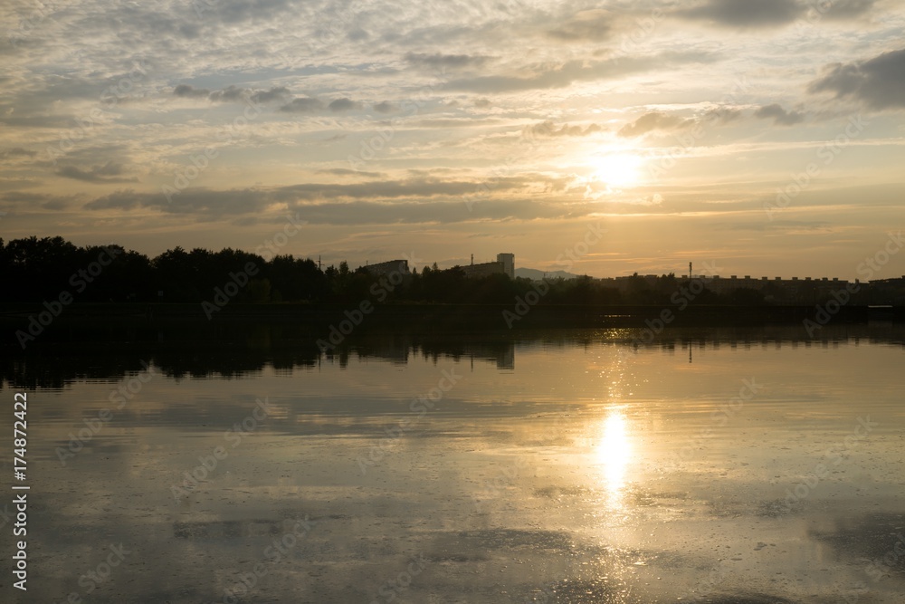 Colorful sunset on the lake with reflections of hills, trees and buildings. Slovakia