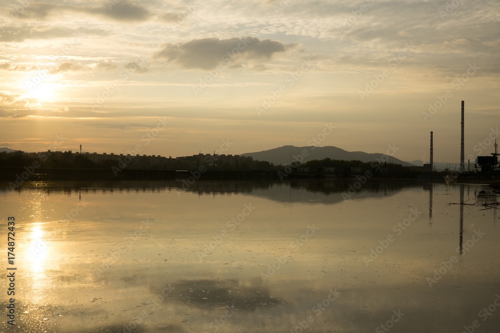 Colorful sunset on the lake with reflections of hills, trees and buildings. Slovakia