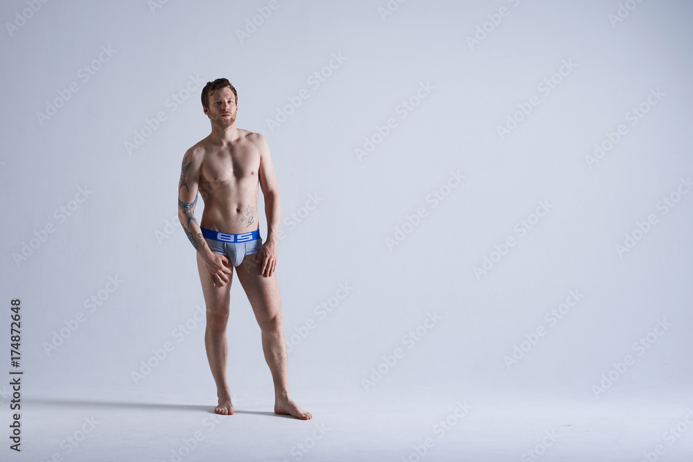 Obraz premium People, style and fashion concept. Full length isolated portrait of handsome muscular athletic adult European male model with beard posing in studio for underwear advertisement or commercial