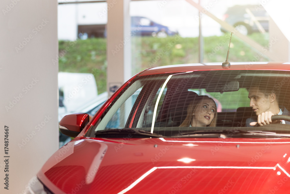 Happy couple in car/ Young beautiful couple man and girl is riding on a new red car and talking. Happy couple in car/ Young beautiful couple man and girl is riding on a new red car and talking.