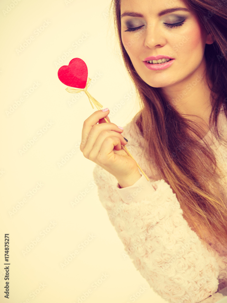 Flirty woman holding red wooden heart on stick Flirty woman holding red wooden heart on stick
