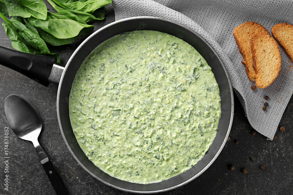 Frying pan with tasty spinach sauce on table Frying pan with tasty spinach sauce on table