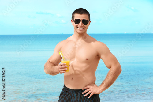 Handsome young man with drink on sea beach