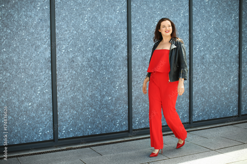 Beautiful overweight woman in red pantsuit walking on city street Beautiful overweight woman in red pantsuit walking on city street