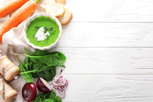 Composition with delicious spinach soup and spices on wooden background