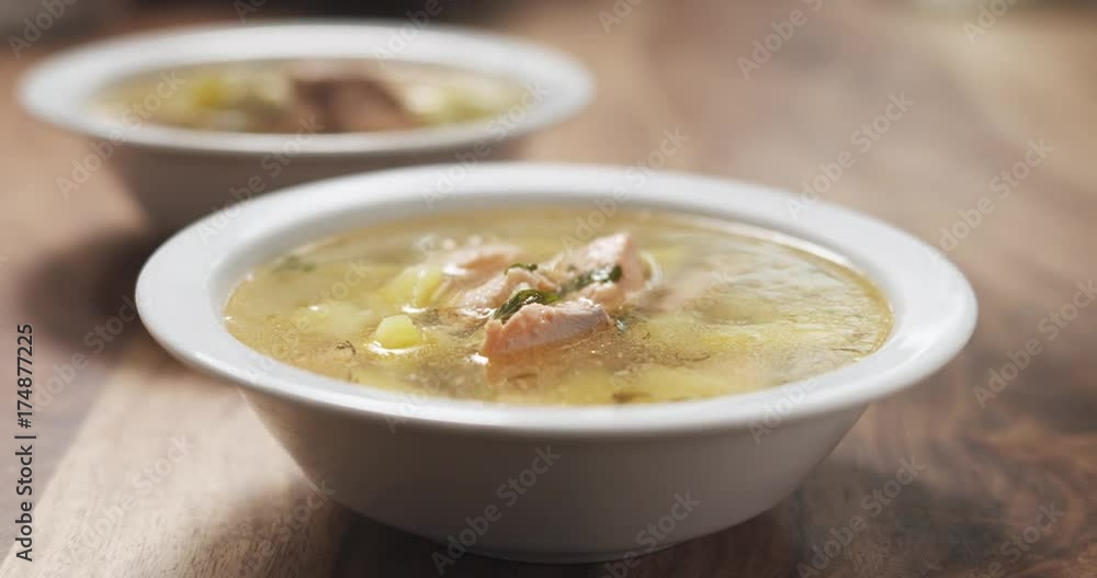 Slow motion closeup pour fish soup with salmon into bowl Slow motion closeup pour fish soup with salmon into bowl