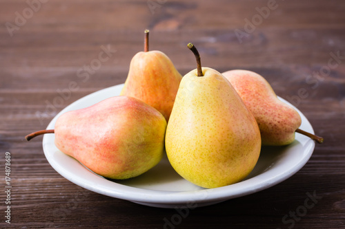 A few pears on a plate on a wooden table
