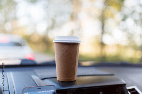 Paper Cup with coffee on the dashboard of the car blurred green background photo