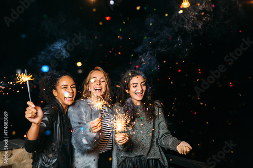 Three happy women having fun with sparklers. Outdoor party.
