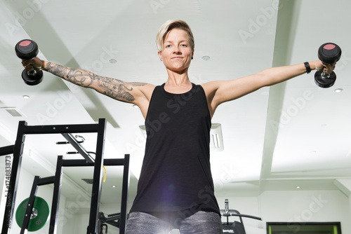 Active Woman Doing Dumbbell Shoulder Flyes in Gym photo