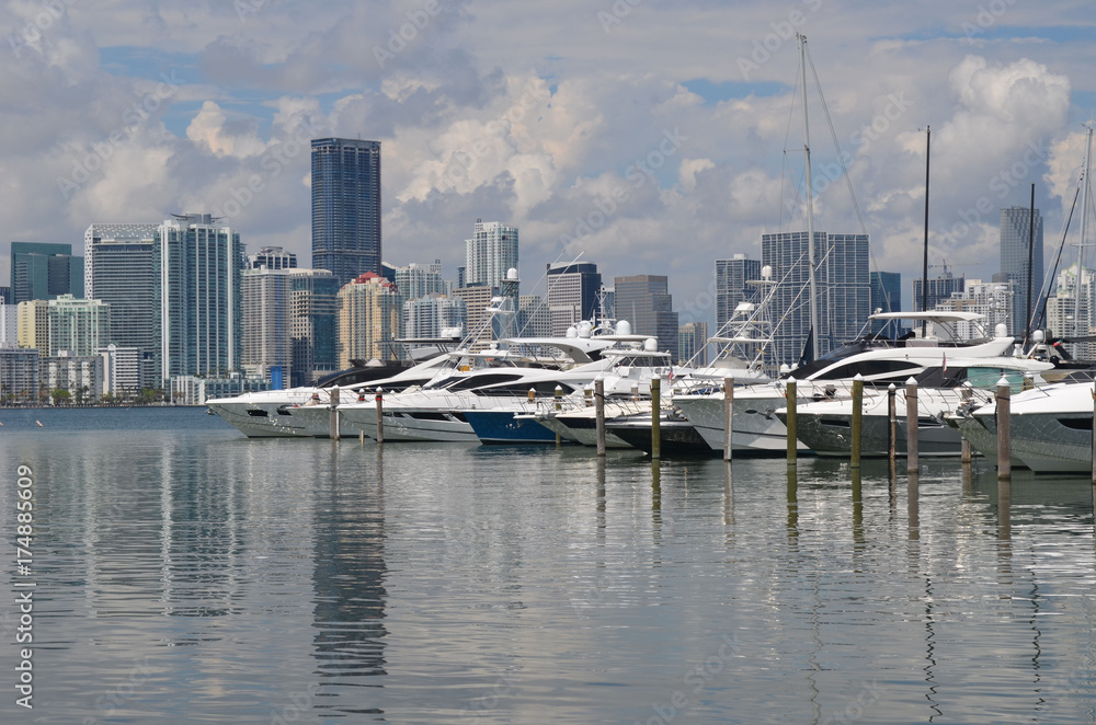 A wide variety of recreational boats moored at a Key Biscayne marina with Miami condo and commercial building skyline in the background.