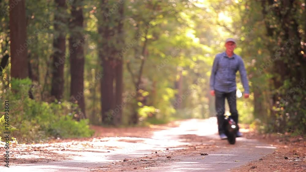Electrical personal transport. Man riding mono wheel in autumn park road. Electrical personal transport. Man riding mono wheel in autumn park road.