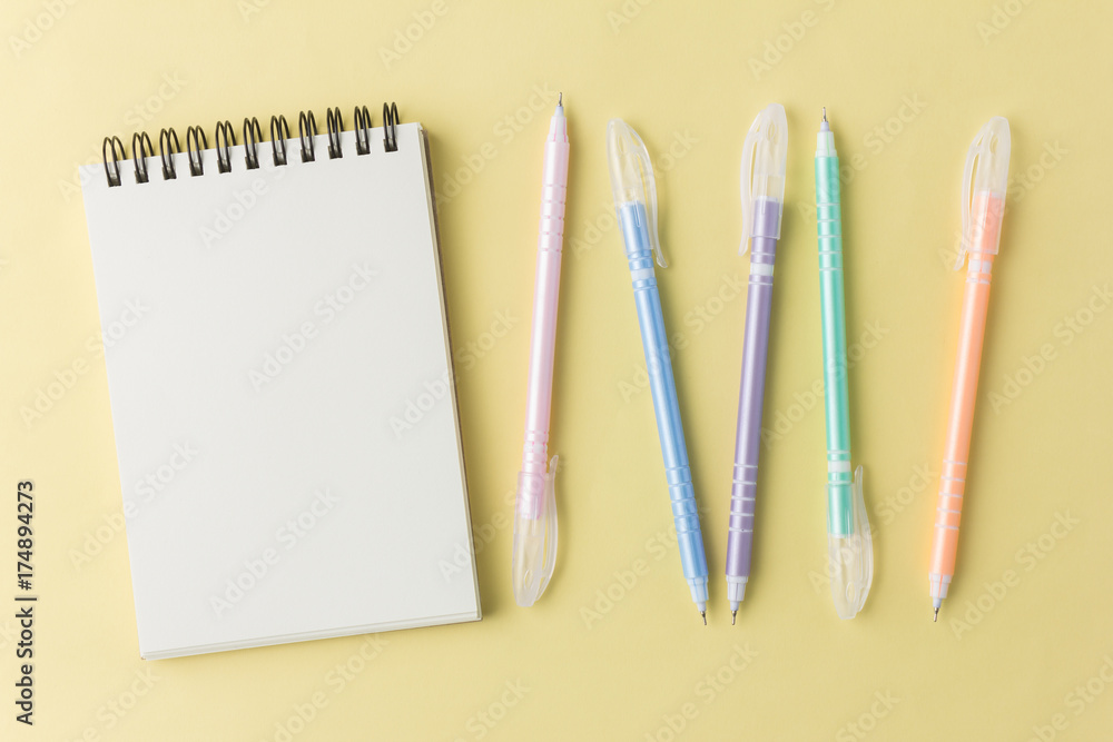 notebook with colorful pen on yellow background notebook with colorful pen on yellow background