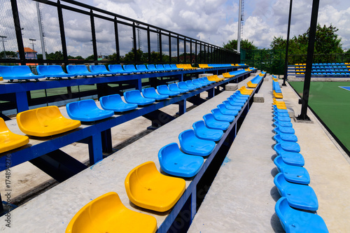Empty tennis stadium chairs.Row of seats in tennis stadium. Blue and yellow chairs in a sport stadium.