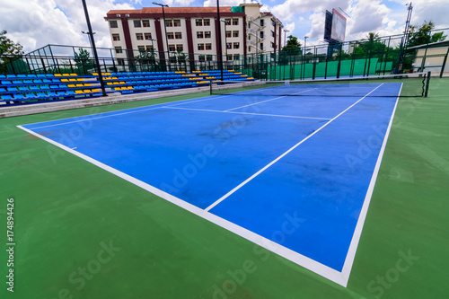 Blue tennis court with  lines. Clouds blue sky background. © Pattadis