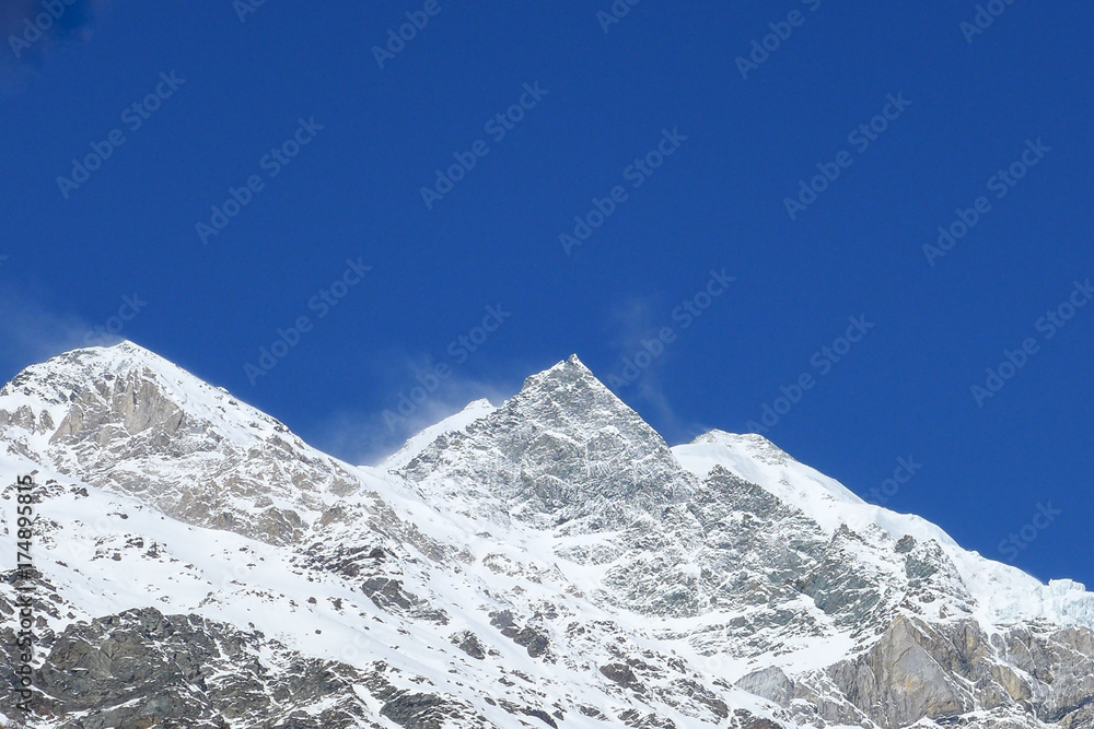 The mountains are covered with snow on blue sky in the sunny day