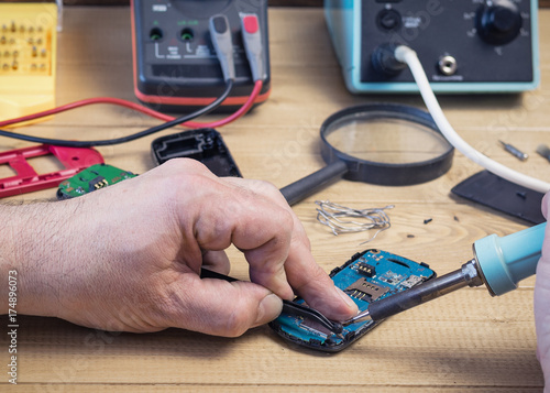 Man repairing a faulty circuit Board of a mobile phone.