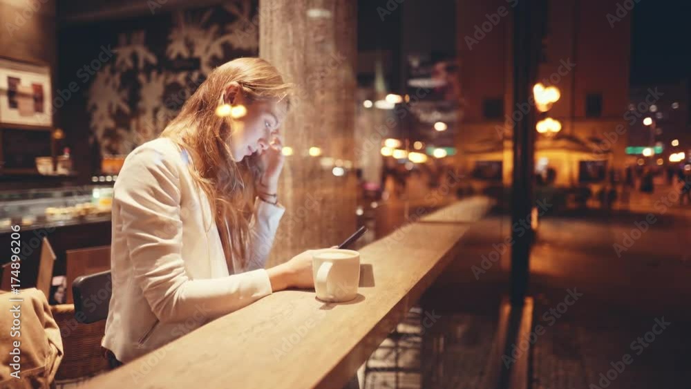 Portrait of Young Woman Using Digital Tablet in Cafe at Night. 4K. Elegant businesswoman drinking coffee, reading news on tablet computer, using app, shopping, communicating in social media.