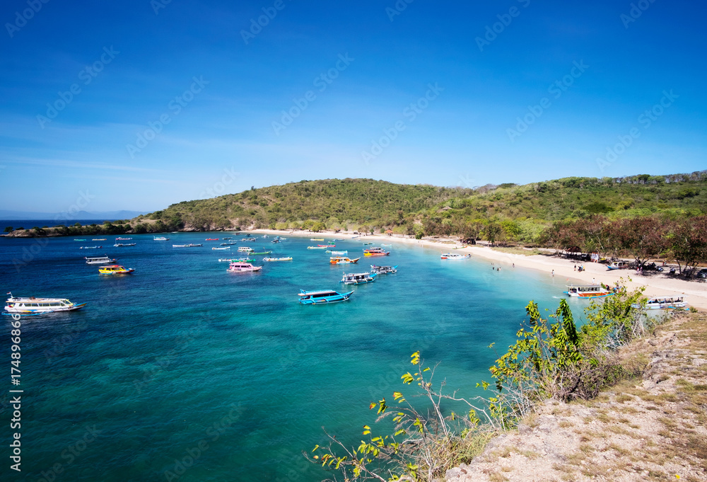 Boats with tourists arriving to beautiful beach on tropical island, Lombok, Indonesia