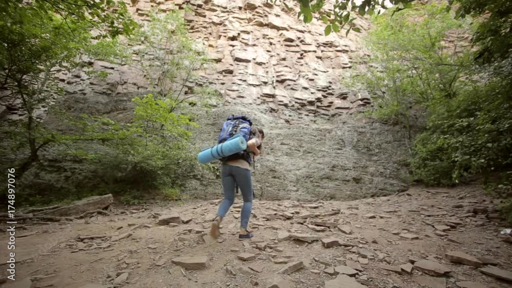 Young woman hiker in mountain forest. Girl climber climbs the mountain and looks at the view. Young woman hiker in mountain forest. Girl climber climbs the mountain and looks at the view.
