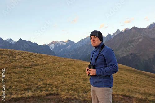 hiker with binoculars stands on a background of mountains. Svaneti  Georgia
