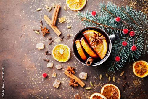 Cup of christmas mulled wine or gluhwein with spices and orange slices on rustic table top view. Traditional drink on winter holiday. Vintage toned.