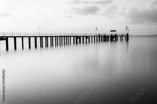 Long exposure view of a pier on a lake at sunset, with beautiful, soft tones and perfectly still water