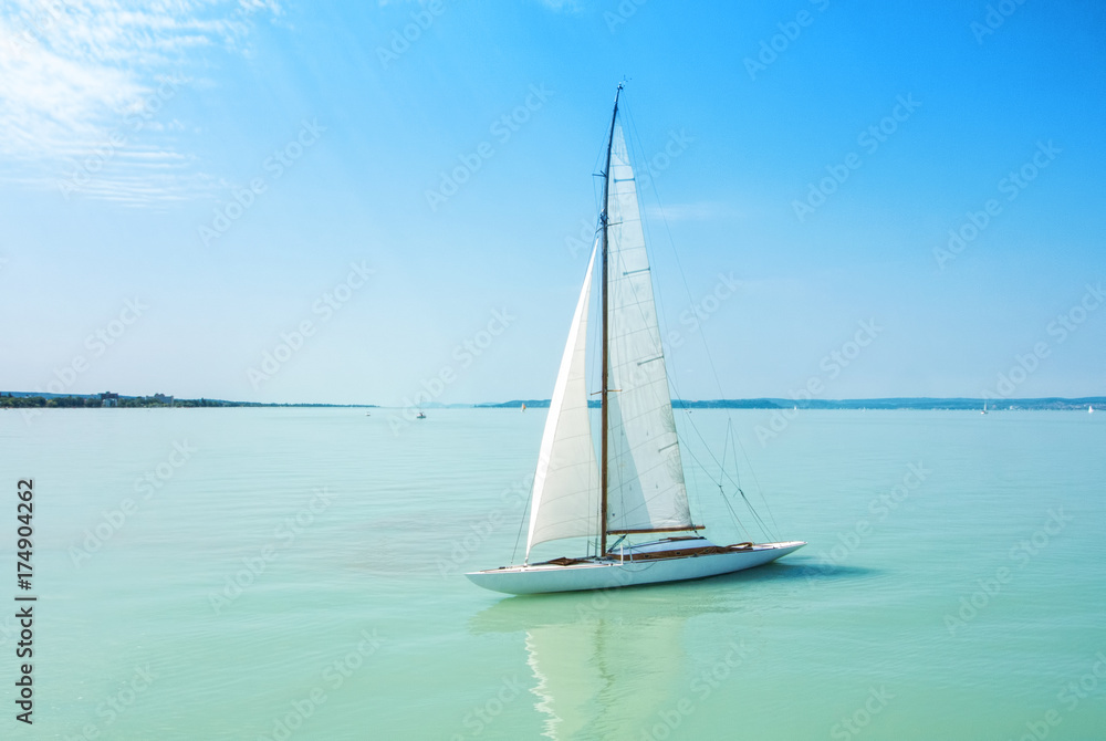 A view from a ship to bright Balaton lake water and a white yacht on sunny summer day, Hungary.