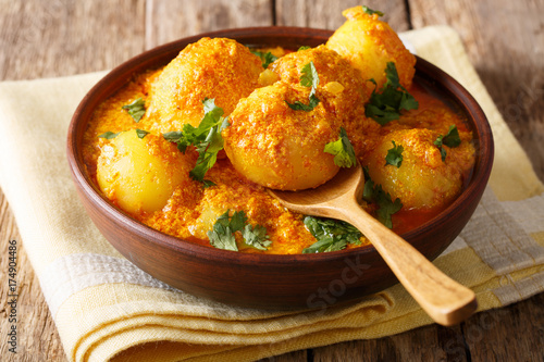 Kashmiri dum aloo: spicy potato with sauce closeup on the plate on the table. Horizontal photo