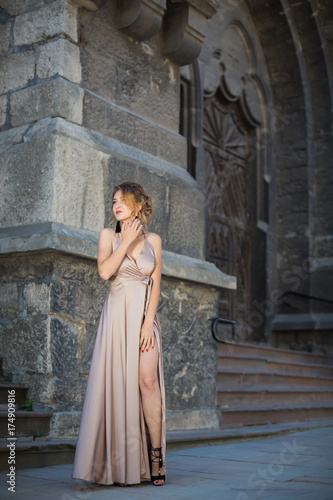 The young elegant attractive woman standing outdoor against the background of old building and looking aside